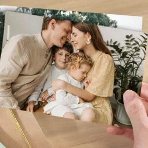 Família feliz segurando foto impressa com Alfafotobook Pro, álbum de fotos personalizado e de alta qualidade.