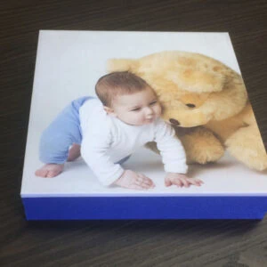 Álbum fotográfico infantil personalizado Alfafotobook Pro com foto de bebê e ursão de pelúcia.