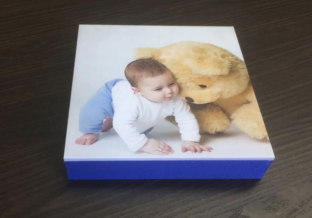 Álbum fotográfico infantil personalizado Alfafotobook Pro com foto de bebê e ursão de pelúcia.