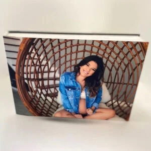Retrato de uma mulher sorridente em capa de álbum Fotobook Pro com design rattan, destacando qualidade e personalização.