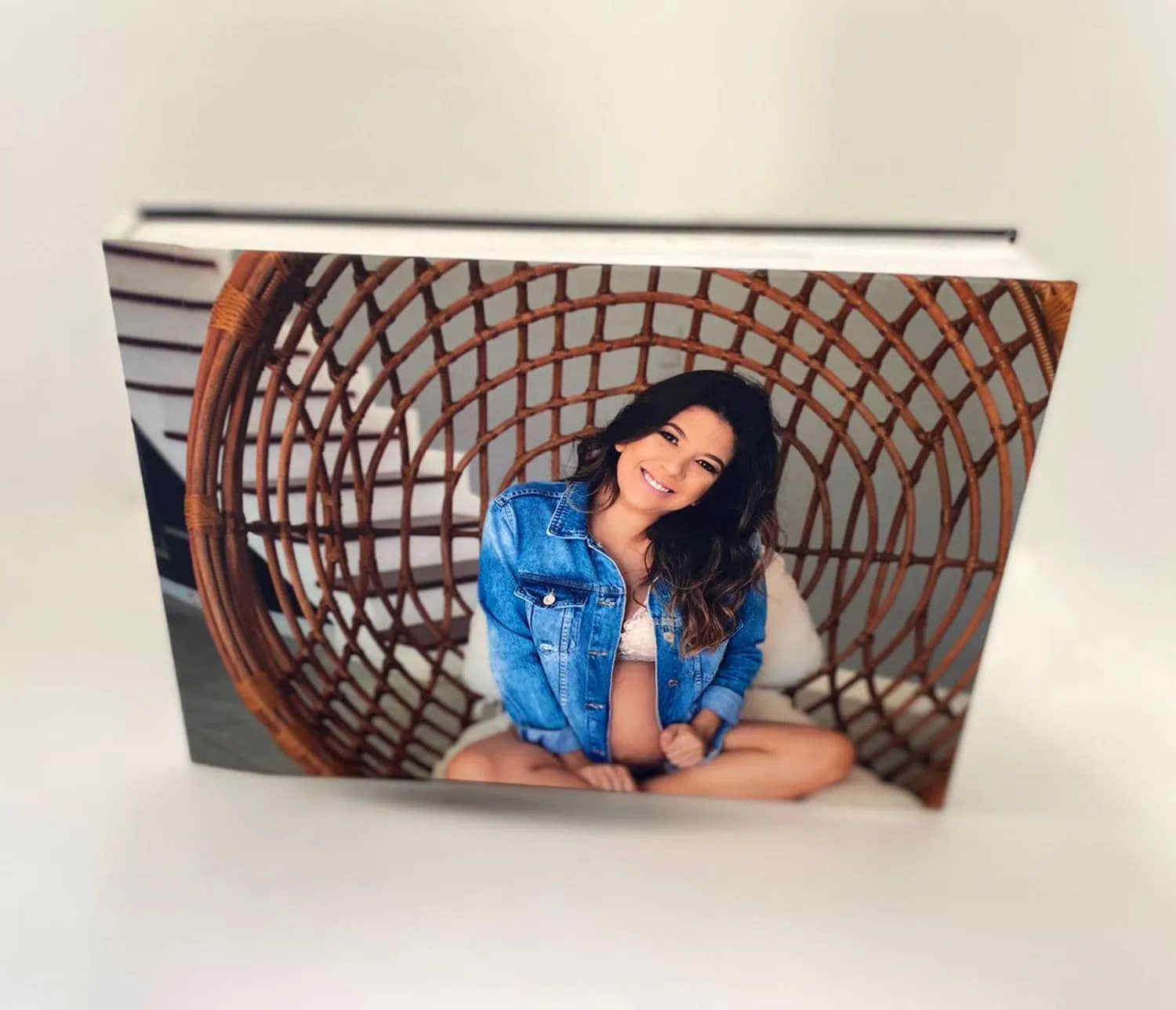 Retrato de uma mulher sorridente em capa de álbum Fotobook Pro com design rattan, destacando qualidade e personalização.